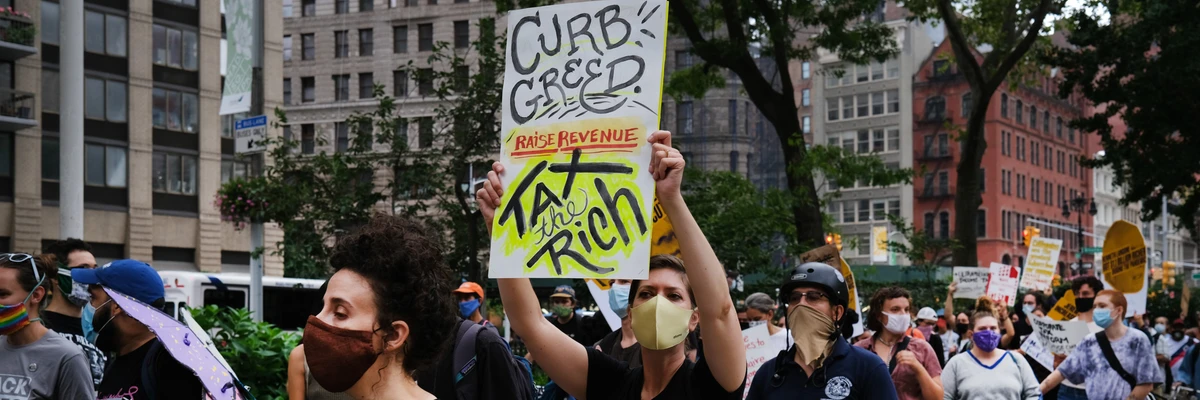 Placard reads Curb Greed Tax the Rich