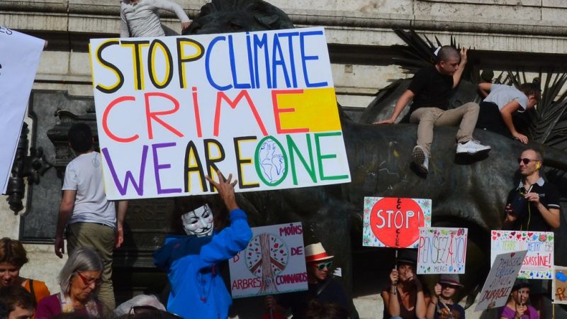 Protest banner reads Stop Climate Crime. We are One.